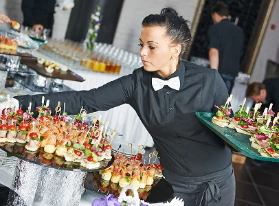 Serveuse en chemise noire et nœud papillon blanc, présentant des canapés à Suresnes près de Nanterre en Hauts-de-Seine 92