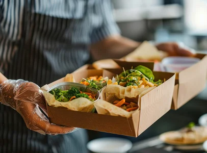 Mains gantées tenant une boîte repas avec divers plats végétariens frais à Suresnes près de Nanterre en Hauts-de-Seine 92