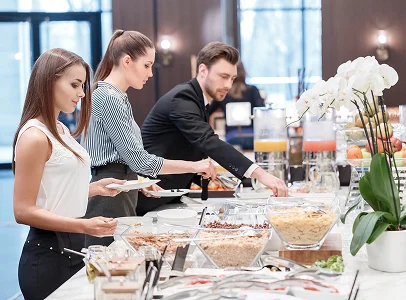Trois personnes se servent à un buffet de petit-déjeuner avec céréales, fruits et jus à Suresnes près de Nanterre dans les Hauts-de-Seine 92