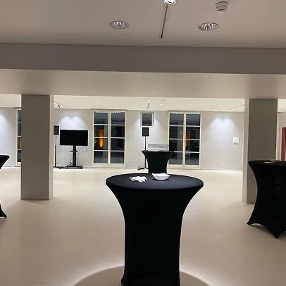 Grande salle blanche avec tables hautes noires, écran et système audio à Suresnes près de Nanterre dans les Hauts-de-Seine 92